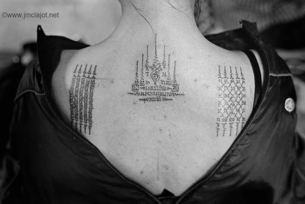 Attractive Small Thai Spiritual Tattoo On Upper Back For Girls