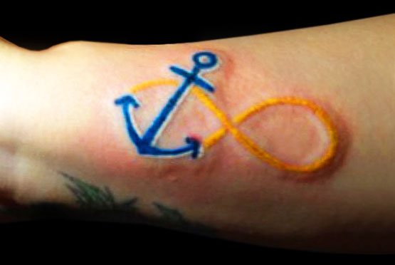 Blue Anchor With Yellow Infinity Tattoo On Arm