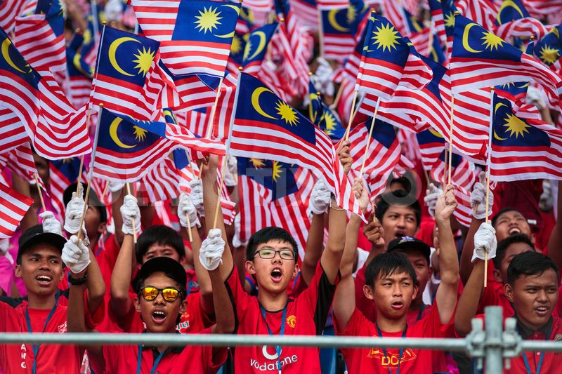 Group Of Malaysian People Waving Flags During Malaysia Day Celebration