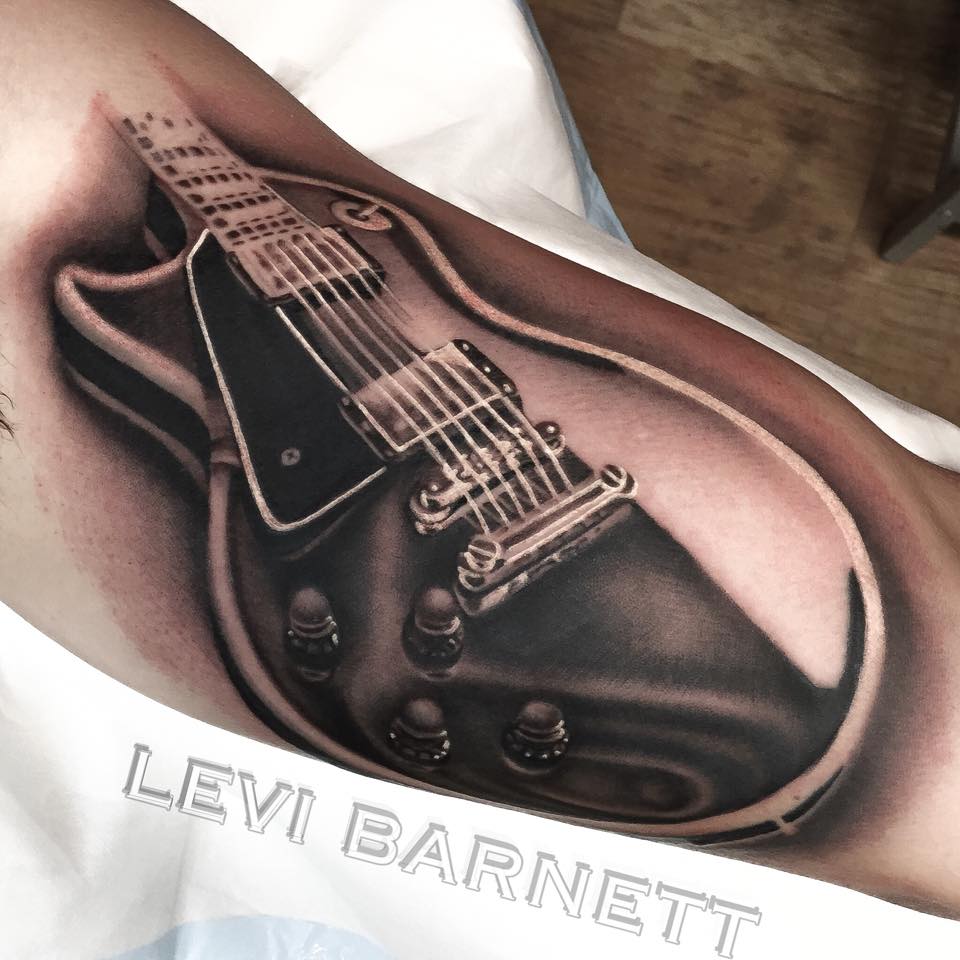 Black and grey guitar tattoo on arm by Levi Barnett