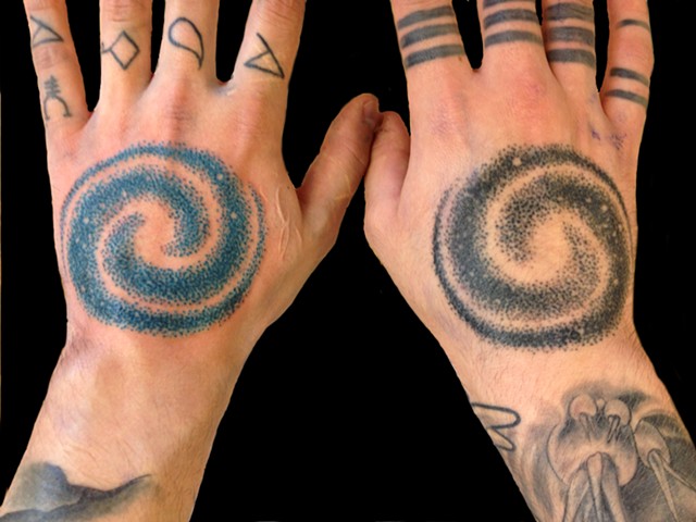 Different Colored Spiral Galaxy Tattoos On Hands