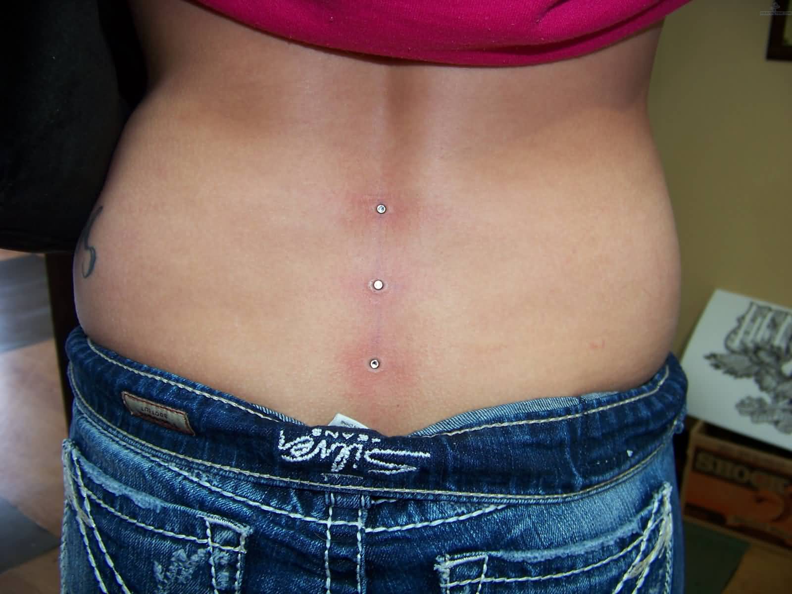 Girl With Silver Dermals Lower Back Piercing