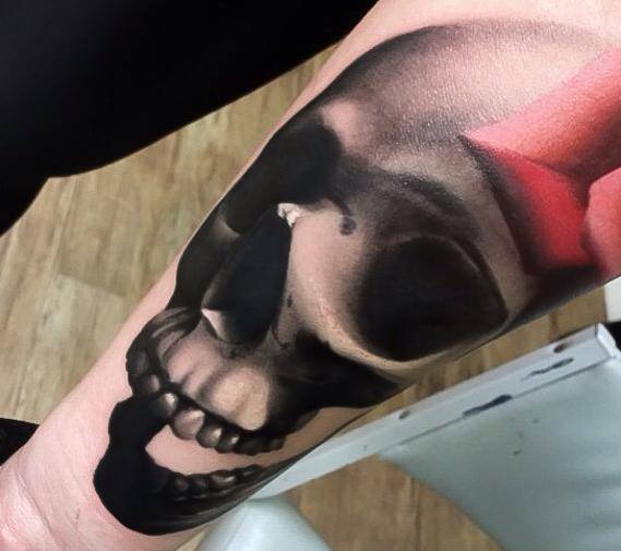 Laughing skull tattoo on arm by Levi Barnett