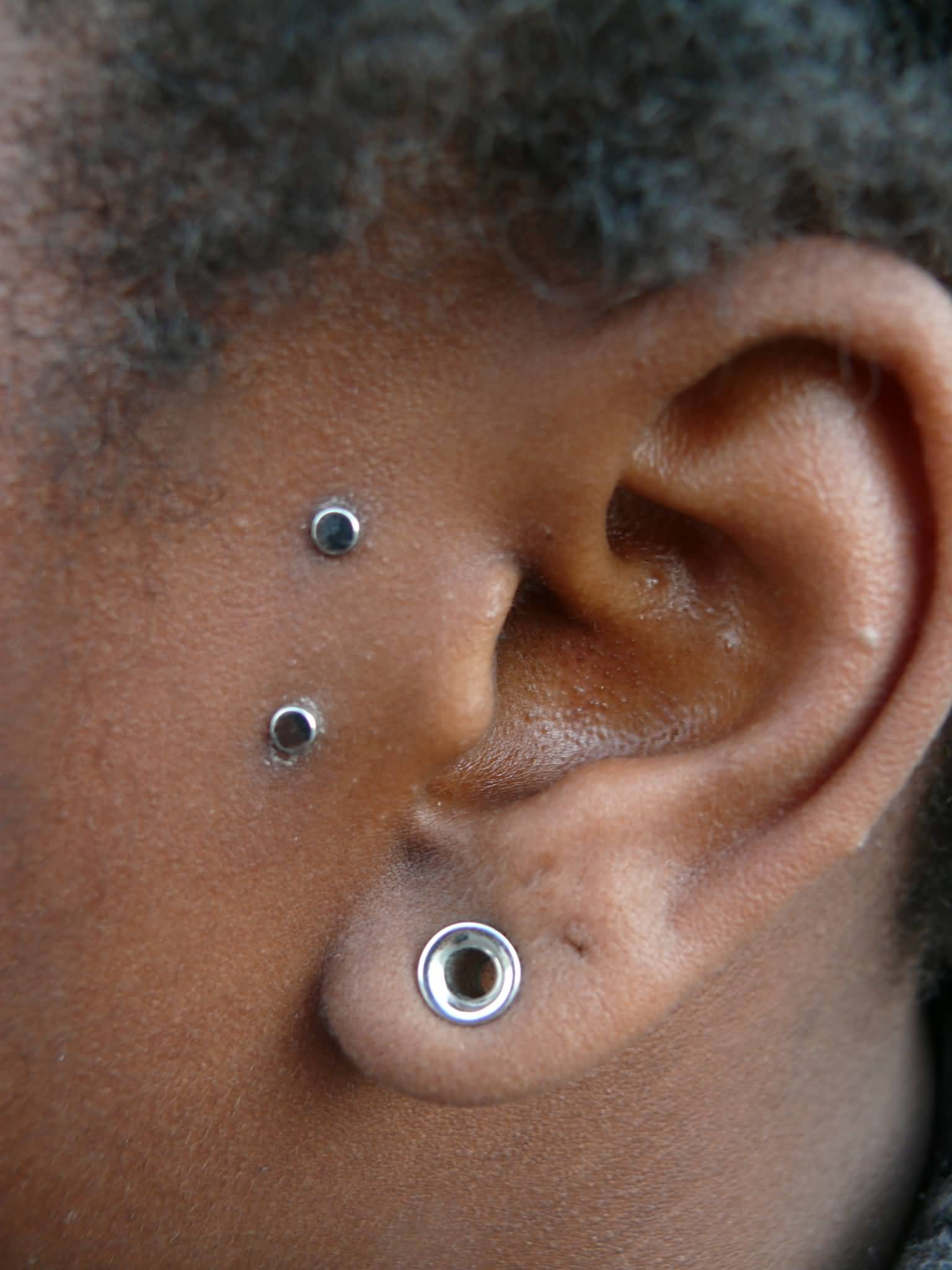 Lobe Stretching And Surface Tragus Ear Piercing On Left Ear