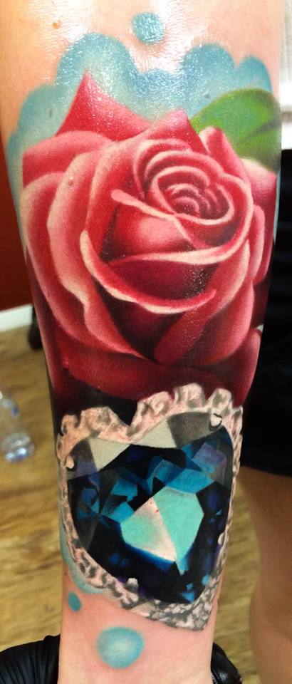 Red rose with crystal heart pendant tattoo on arm by Levi Barnett