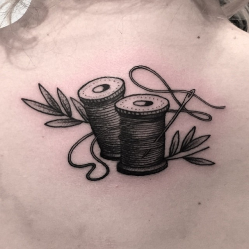 Black Ink Sewing Spools Tattoo On Upper Back