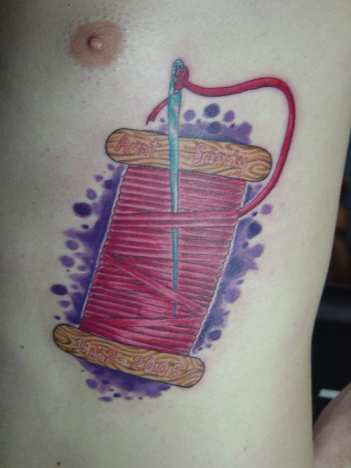 Color Sewing Needle And Thread Tattoo On Chest