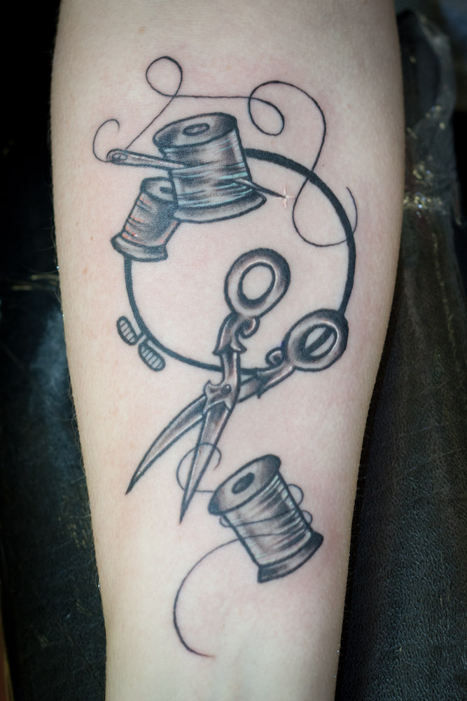 Grey Sewing Tattoo On Forearm By Mange