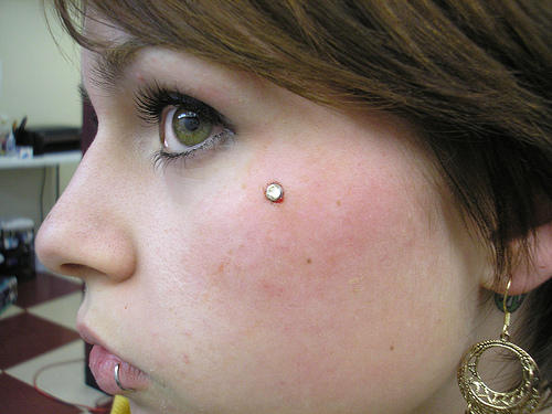 Lower Lip Ring And Microdermal Piercing On Face