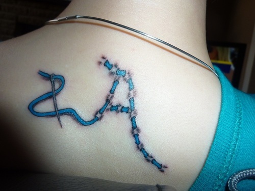 Needle And Thread Sewing Blue Ink Tattoo On Upper Back For Girls