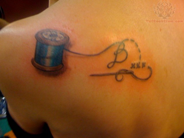 Sewing Needle And Spool Tattoo On Left Back Shoulder
