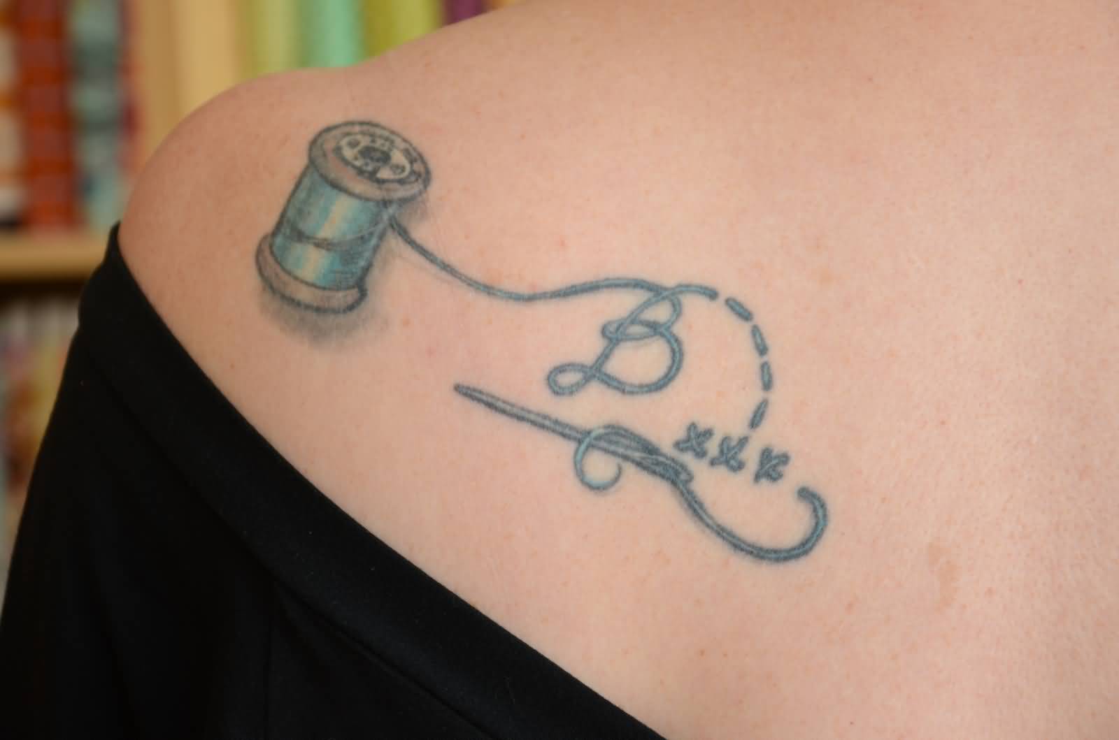 Sewing Needle With Spool Tattoo On Left Back Shoulder