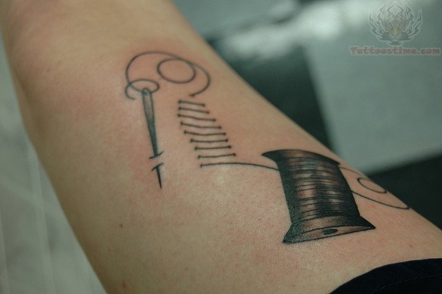 Spool And Sewing Needle Tattoo On Forearm