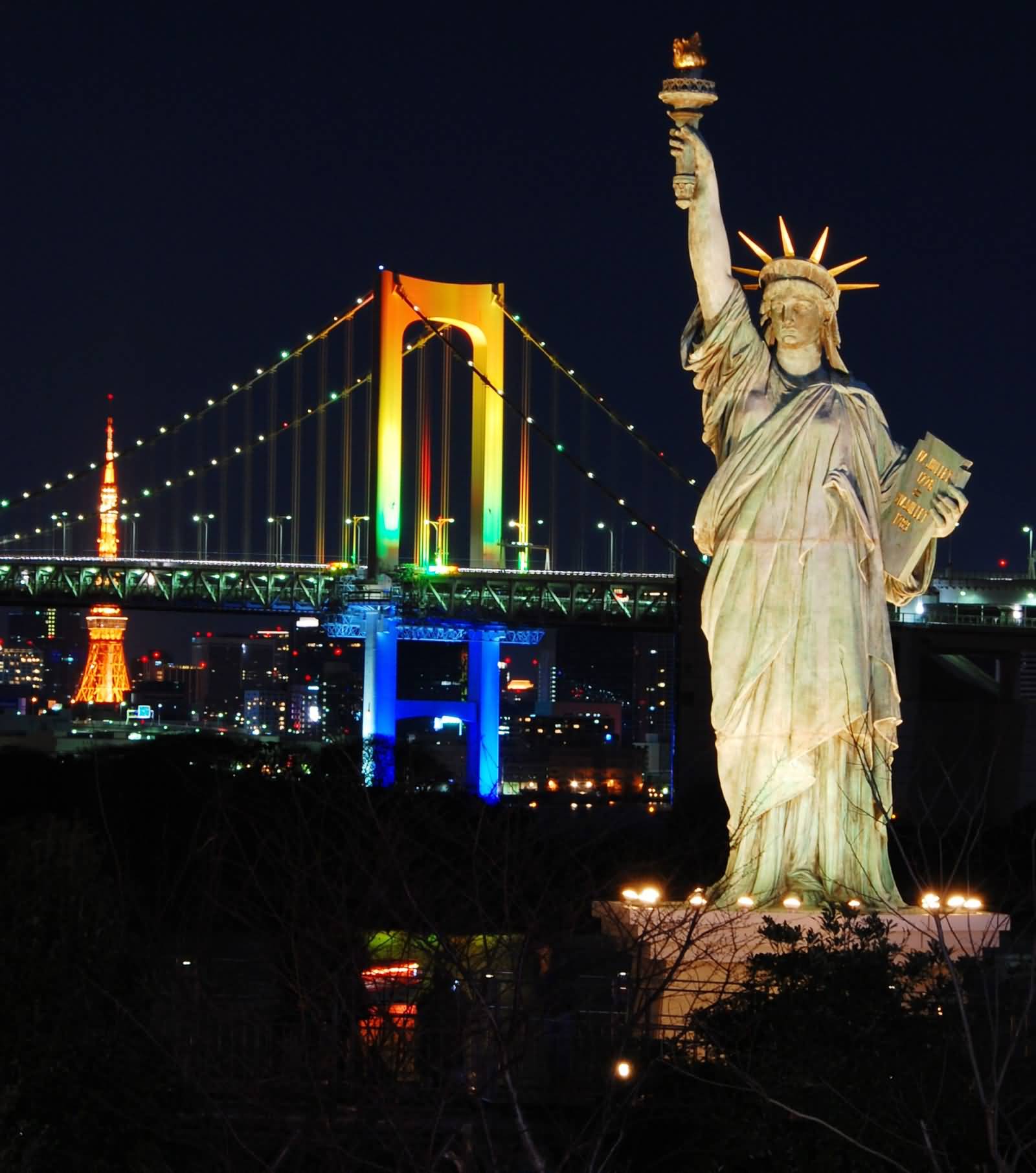 Statue Of Liberty And Rainbow Bridge Lit Up At Night