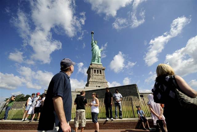 Visitors Pose For Photographs In Front Of Statue Of Liberty In New York