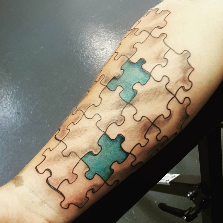 Blue And Black Puzzle Tattoo On Forearm