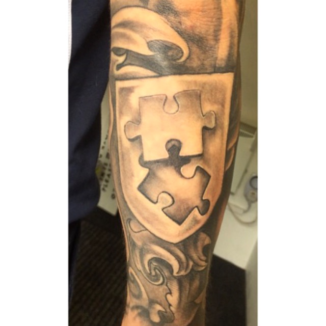 Grey Ink Puzzle Shield Tattoo On Sleeve
