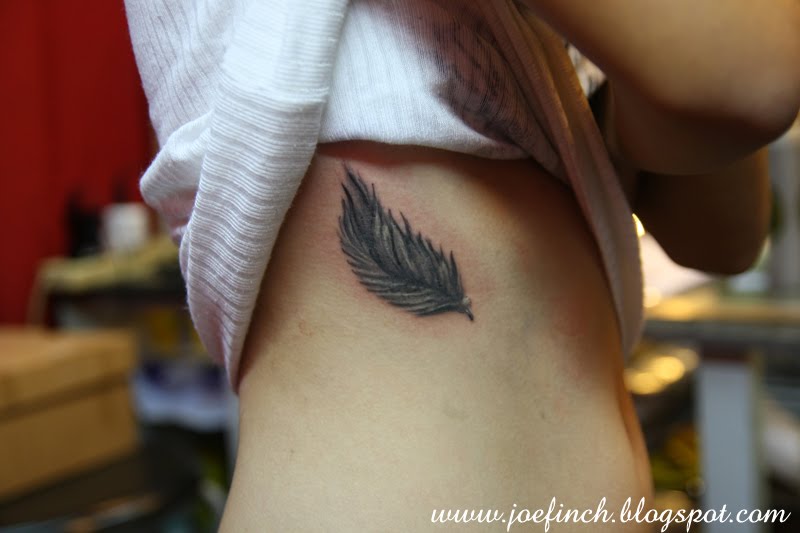 Small Black Feather Tattoo On Rib Cage.