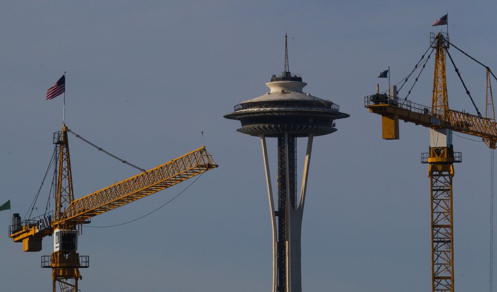 The Space Needle Is Seen Between Two Cranes In Seattle South Lake