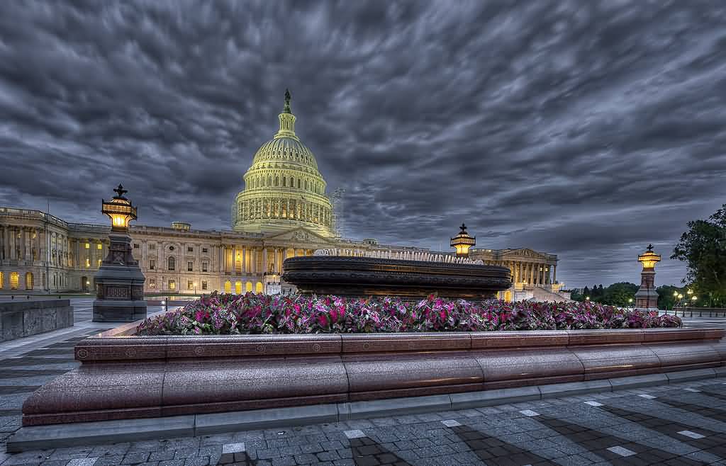 United States Capitol With Black Clouds And Night Lights