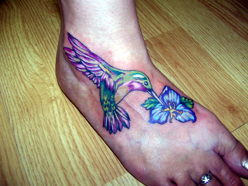 Attractive Hummingbird And Blue Flower Tattoo On Foot