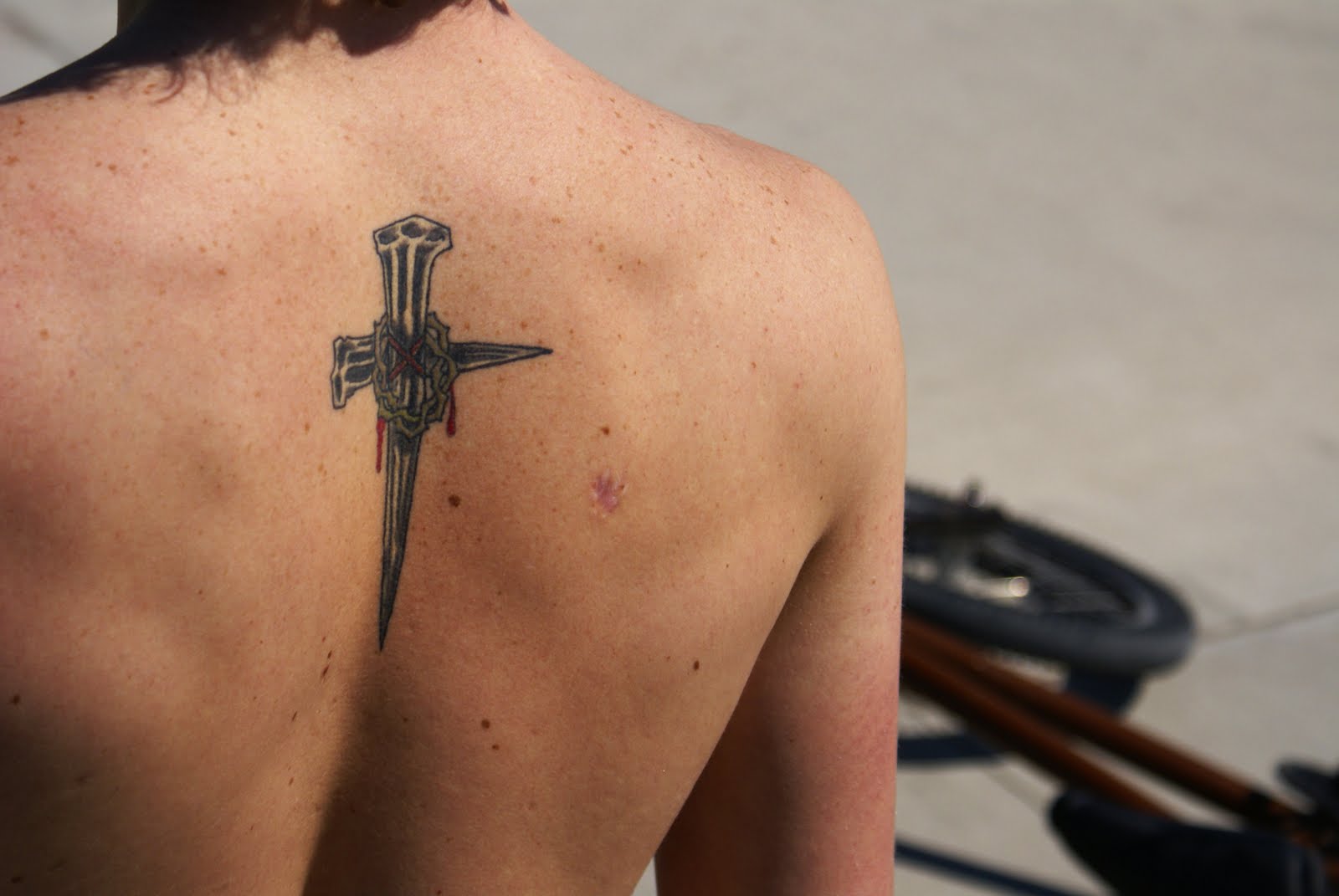 Black Ink Christian Nail Cross Tattoo On Upper Back