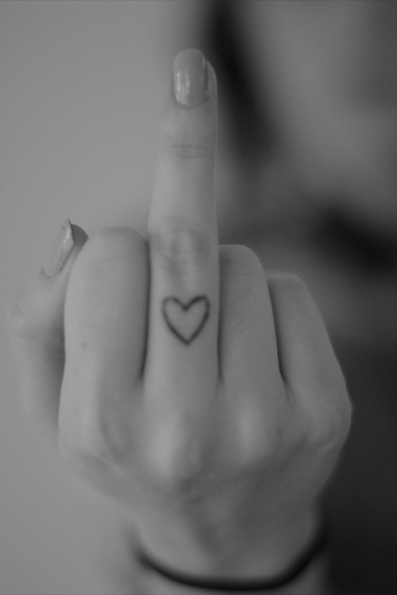 Girl Showing Small Heart Tattoo On Middle Finger