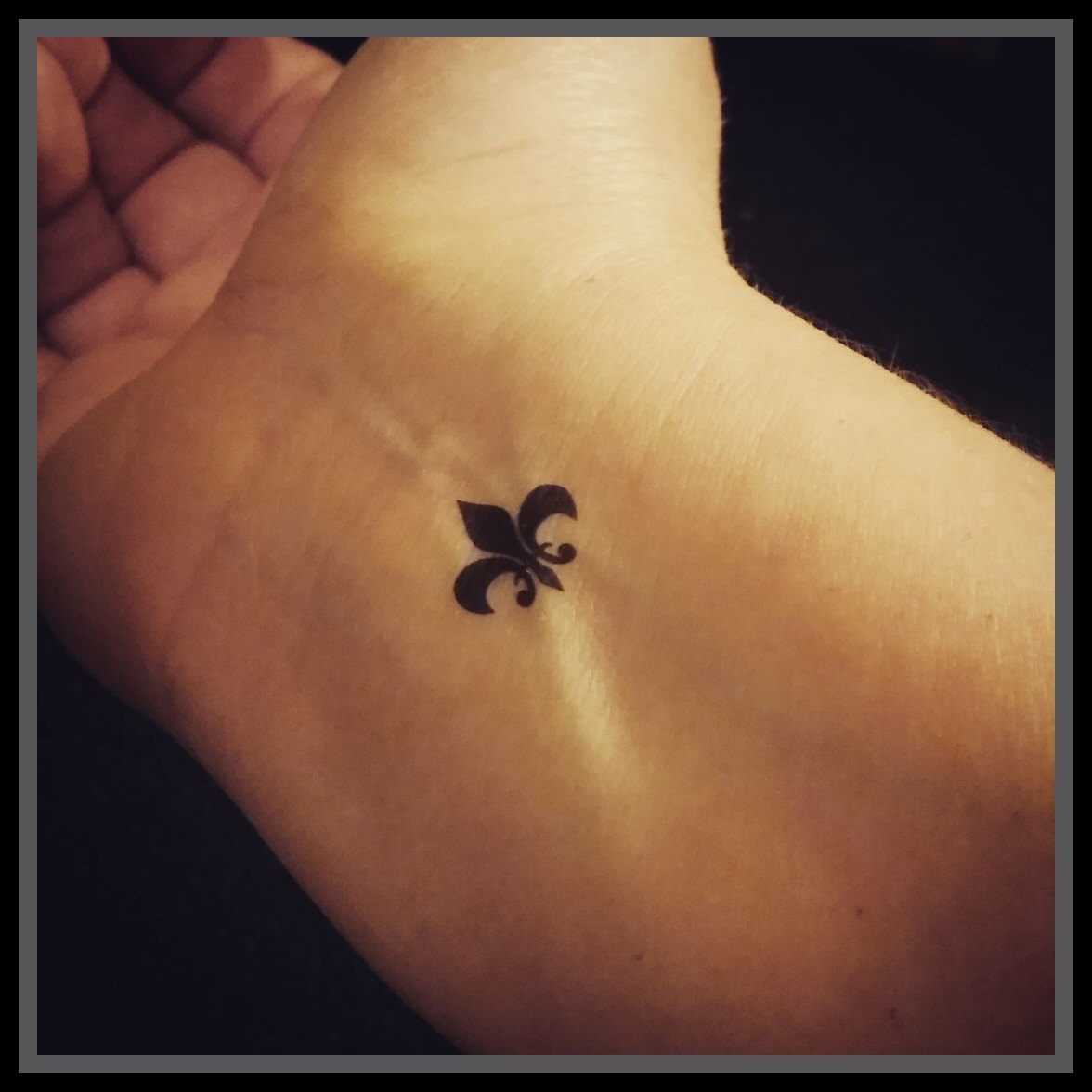 Tiny Black Fleur De Lis Tattoo On Right Wrist