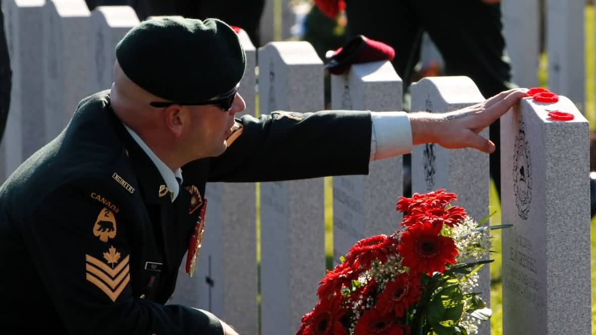 A Soldier Touching Tomb Of A Veteran During Remembrance Day Ceremony