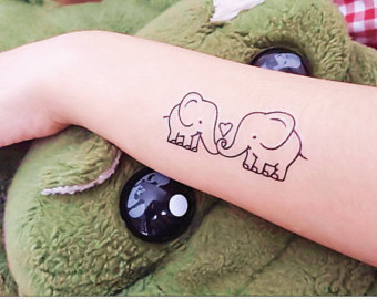 Black Outline Two Small Baby Elephants With Heart Tattoo On Left Arm