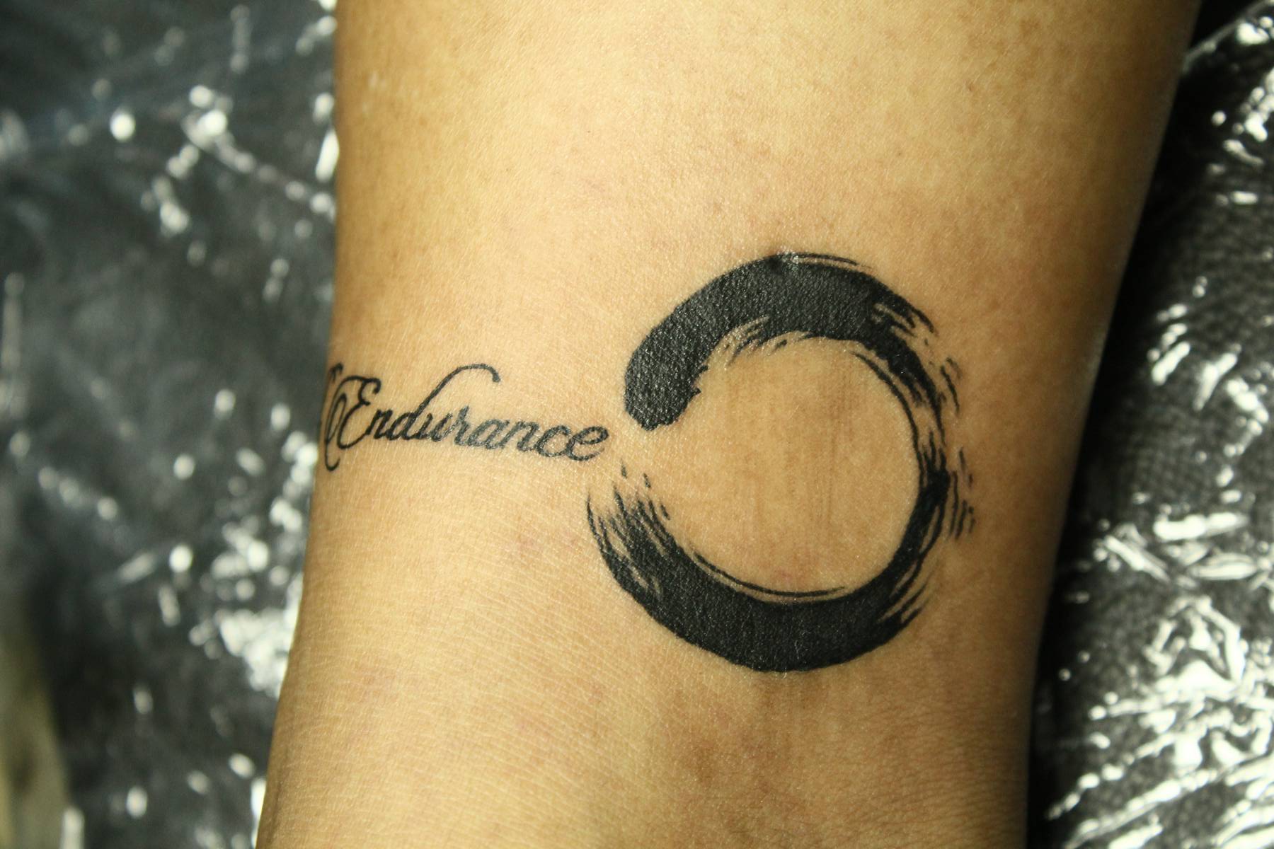 Endurance - Black Ink Zen Circle Tattoo Design For Wrist