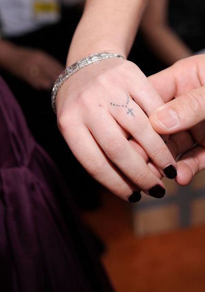 Girl Showing Her Small Rosary Tattoo On Finger