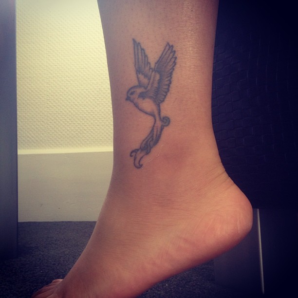 Grey Flying Bird Tattoo On Left Ankle