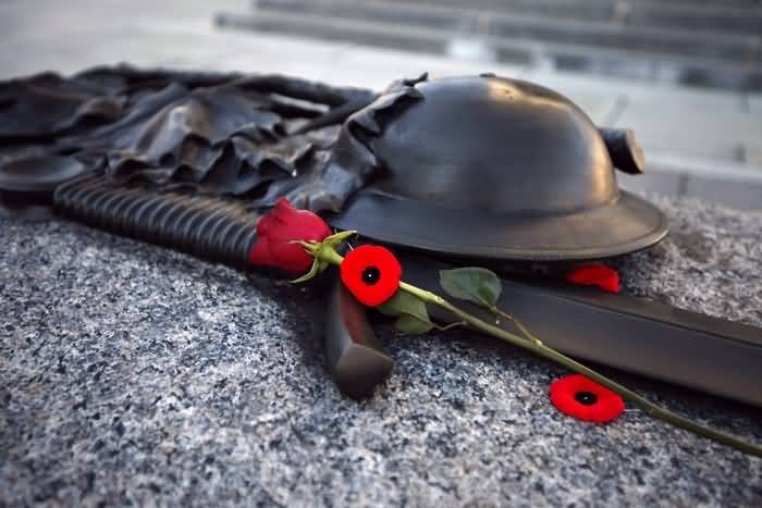 Gun And Helmet Of A Soldier With Poppy And Rose Flower During Remembrance Day Ceremony