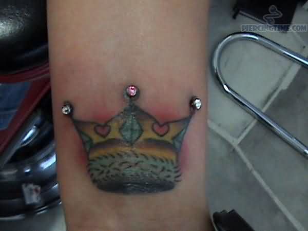 Micro Dermal Piercing And Crown Tattoo On Wrist