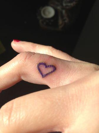 Purple Ink Heart Tattoo On Girl Side Finger