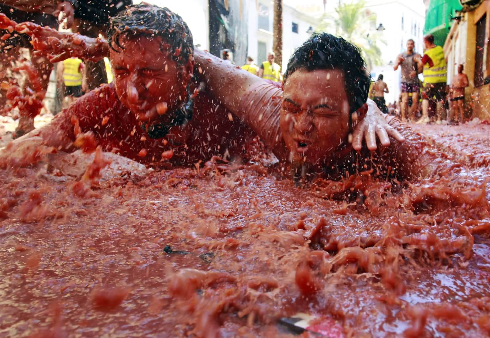 Two Boys Sliding In Tomato Juice During La Tomatina Festival Celebration
