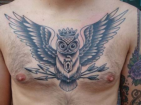 Black And Grey Crown On Owl Head With Arrows Tattoo On Man Chest