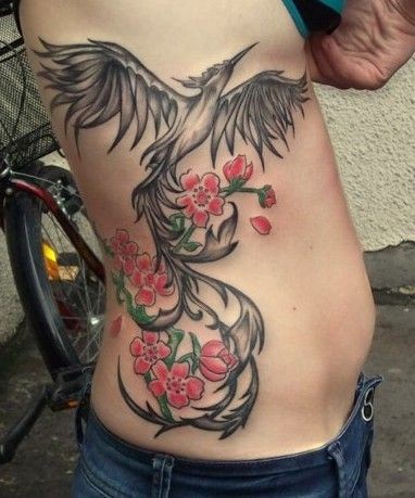 Black And Grey Flying Phoenix With Flowers Tattoo On Right Side Rib