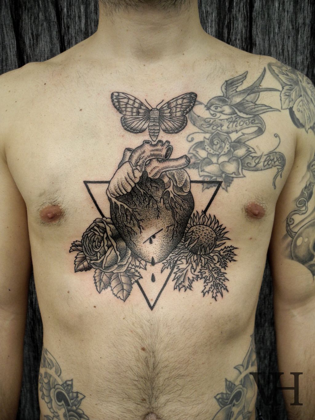 Black And Grey Real Heart With Flowers In Triangle Tattoo On Man Chest