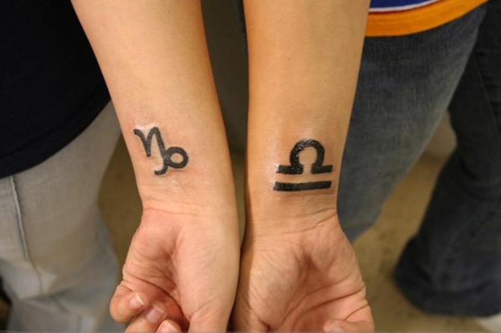 Black Capricorn And Libra Zodiac Sign Tattoo On Couple Wrist