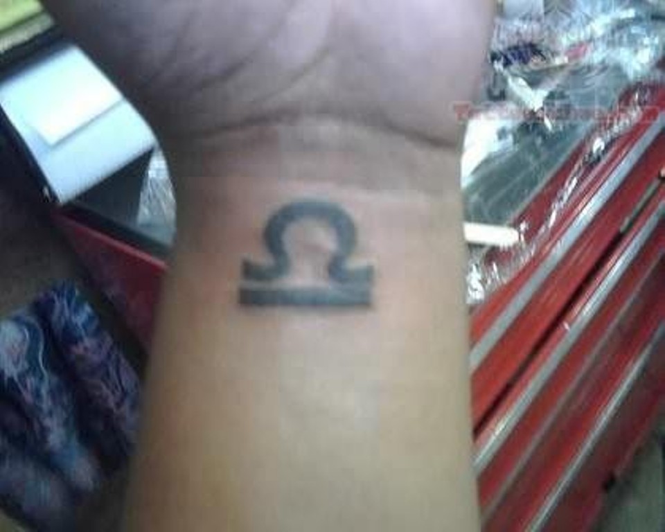 Black Ink Libra Zodiac Sign Tattoo On Left Wrist