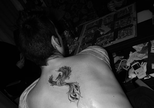 Black Ink Rising Flying Phoenix From The Ashes Tattoo On Upper Back