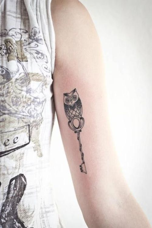 Black Ink Small Owl With Key Tattoo On Left Bicep