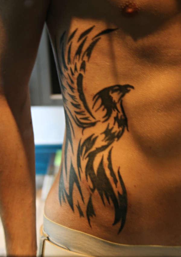 Black Tribal Rising Flying Phoenix From The Ashes Tattoo On Man Right Side Rib