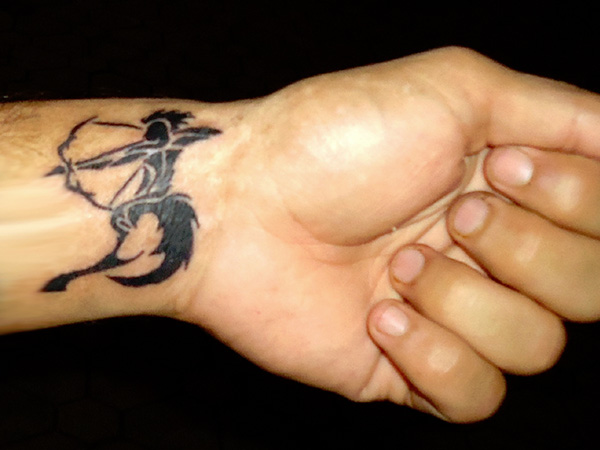 Black Tribal Sagittarius Zodiac Sign Tattoo On Left Wrist