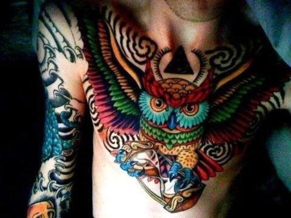 Colorful Flying Owl Bird With Hourglass Tattoo On Man Chest