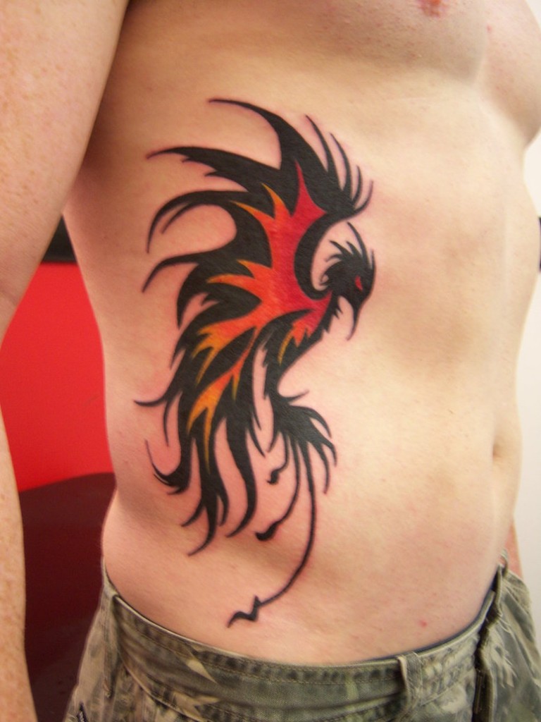 Red And Black Tribal Phoenix Tattoo On Man Right Side Rib