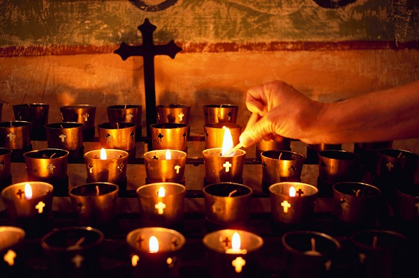 Worshiper Lighting Votive Candle on Altar During All Souls Day