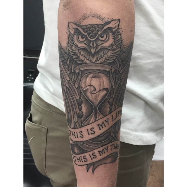 Black And Grey Owl With Hourglass And Banner Tattoo On Right Arm
